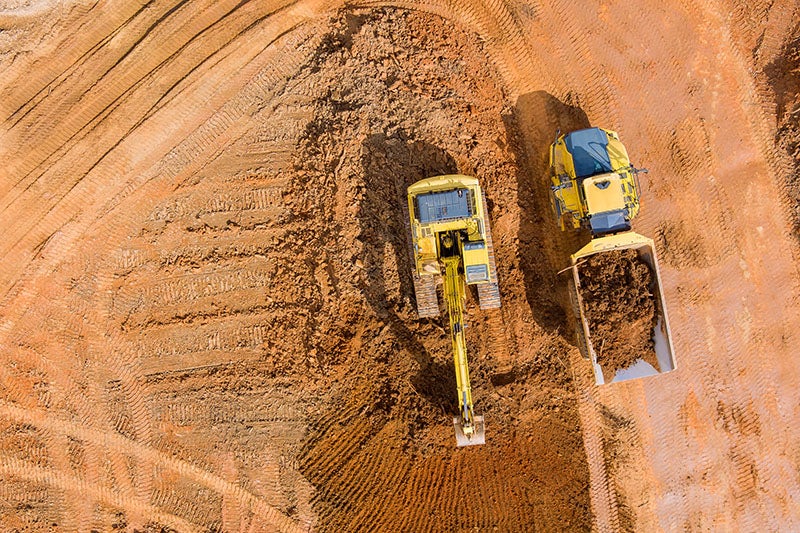 An articulated truck is filled by an excavator.