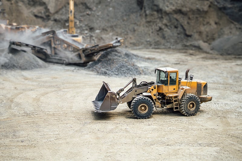A wheel loader sits in a large gravel quarry.