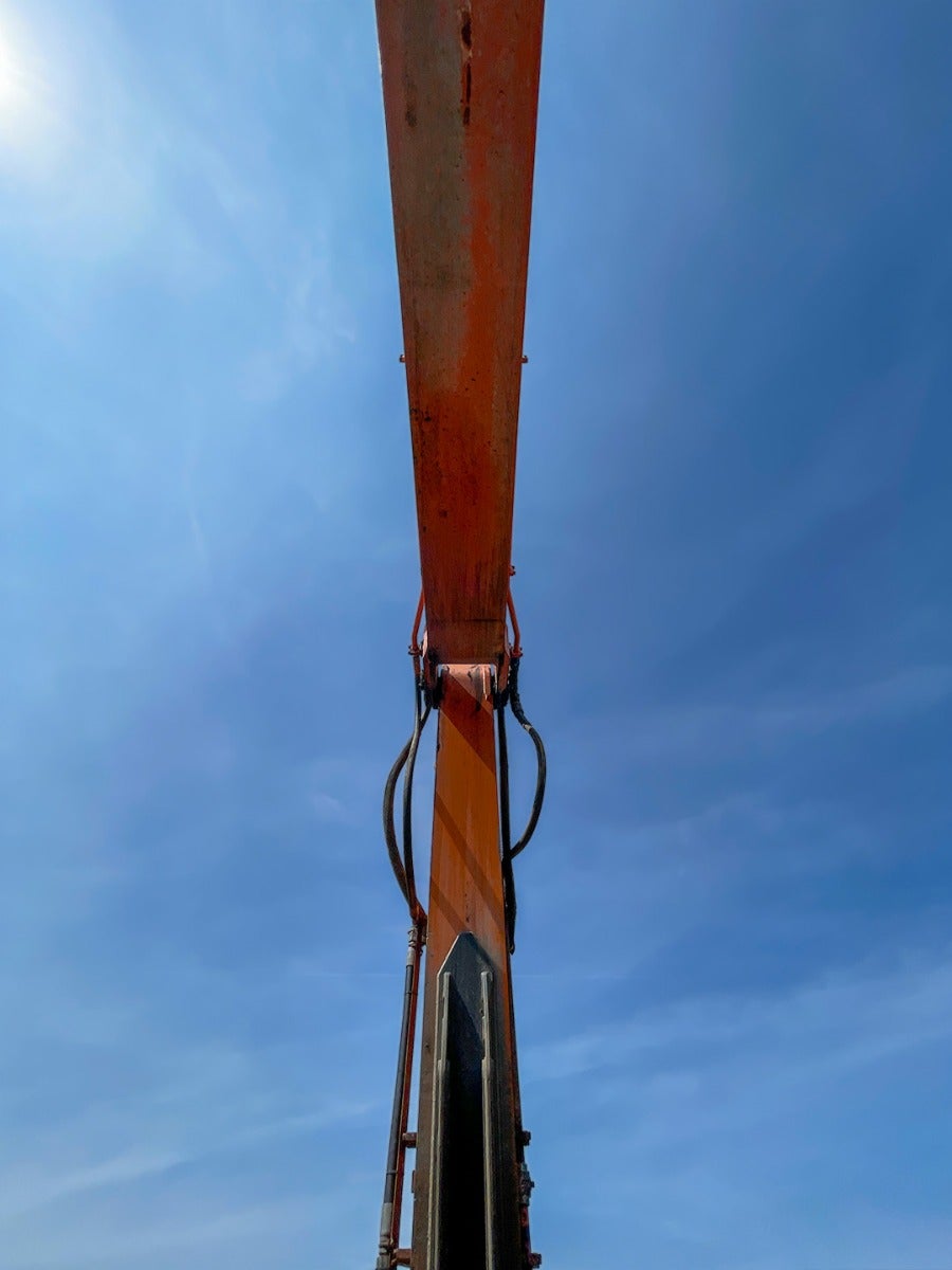 An excavator arm with sky above.