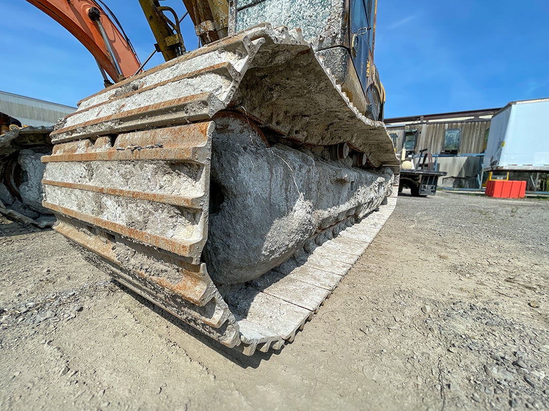 An excavator undercarriage full of debris.